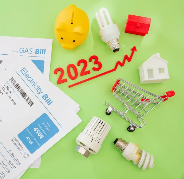 Living cost increase, economic crisis in 2023 flat lay. Shopping cart utilities bills and red rising up arrow on green background.