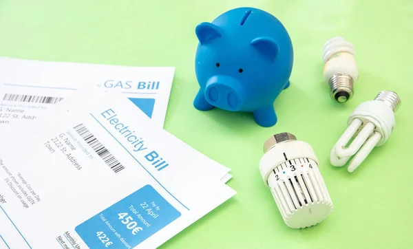 Energy and heating cost increase and saving concept. Electricity and gas bills, piggy bank, light bulb and heating thermostat.