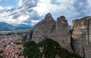 Meteora Yunanistan. Mavi gökyüzü, kayaların üstündeki manastır binaları ve Kalambaka kasabası ve vadisi üzerindeki bulutlarla dolu. Avrupa 'da seyahat hedefi