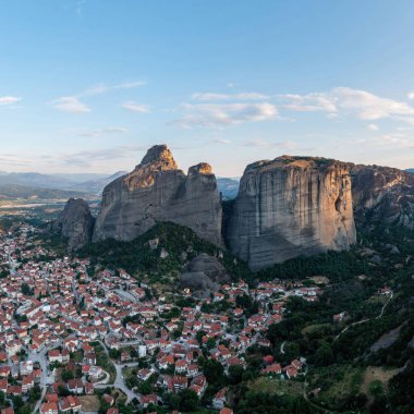 Güneş doğarken meteora Yunanistan, kayaların tepesindeki Manastır binaları ve Kalambaka kasabası ve vadisi üzerindeki bulutlarla mavi gökyüzü. Avrupa 'da seyahat hedefi
