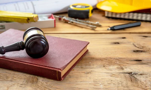 Construction and Labor law. Judge gavel and engineering tools on wooden table, close up view.