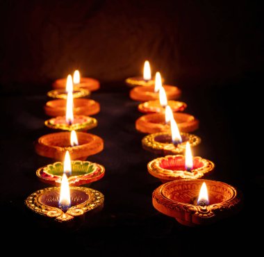 Diwali. Deepavali Hindu festival of lights. Clay diya candles in rows. Oil lamp lit on dark backgroun