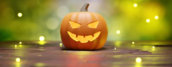 Halloween pumpkin scary eyes glowing in bokeh lights background. Carved lantern, horror night party.