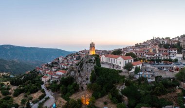 Arachova Yunanistan dağ kenti hava aracı manzaralı. Geleneksel evler ve aydınlatılmış taş kule saati, akşamları..