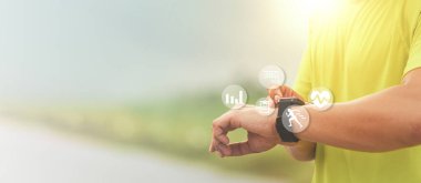 Erkek koşucu modern akıllı saate bakar ve gün batımında açık hava eğitiminden sonra harcanan kalorileri sayar. Egzersiz yaparken sağlık kontrolü teknolojisi kavramı.