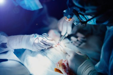 Ameliyathanede cerrahların takım çalışması, eldiven takmak, ameliyat aletleriyle yakın çekim yapmak.