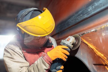 male locksmith mechanic grinder cuts and grinds metal of a car body in a car service, car body repair, restoration of retro cars.