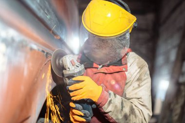 male locksmith mechanic grinder cuts and grinds metal of a car body in a car service, car body repair, restoration of retro cars.