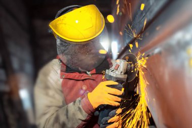 male locksmith mechanic grinder cuts and grinds metal of a car body in a car service, car body repair, restoration of retro cars.