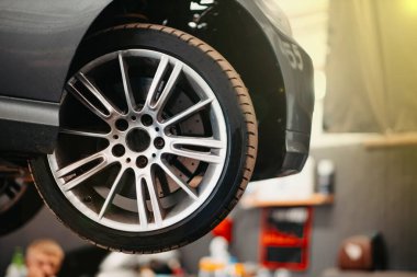 concept of replacing rubber car wheels, alloy wheels, a car on a lift.
