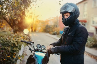Motosikletçi güneşli bir günde motosiklet sürmeden önce deri eldiven giyer..