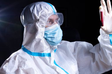 Viroloji üniformalı bir epidemiyoloji doktoru test tüpündeki kanı inceliyor.
