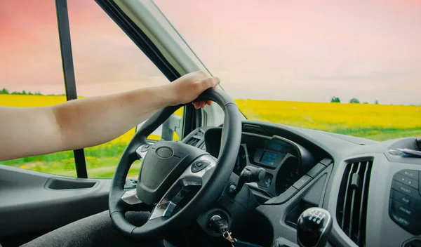 トラック運転手として働くという概念です 夕日と緋色の空を背景に ステアリングホイール上のドライバーの手 旅行ロマンス ロイヤリティフリーのストック写真