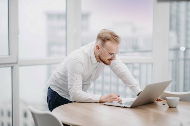 İnternette dizüstü bilgisayarla çalışan genç bir adamın portresi, video konferansı, sosyal ağlarda yazışmalar..