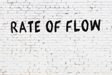Beyaz tuğlalı duvar, siyah boyayla el yazısıyla yazılmış akış hızı.