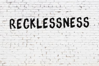 Yazılı beyaz tuğla duvar. Siyah boyayla yazılmış pervasızlık.