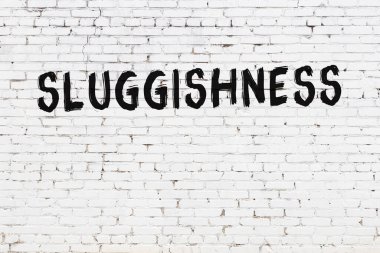 Yazıt uyuşukluğu beyaz tuğla duvara siyah boya ile yazılmış..