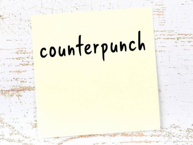 Tahta duvardaki sarı yapışkan notta el yazısıyla yazılmış kontra yumruk.