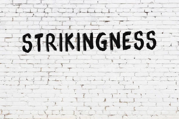 Siyah boyayla yazılan beyaz tuğlalı bir duvar.