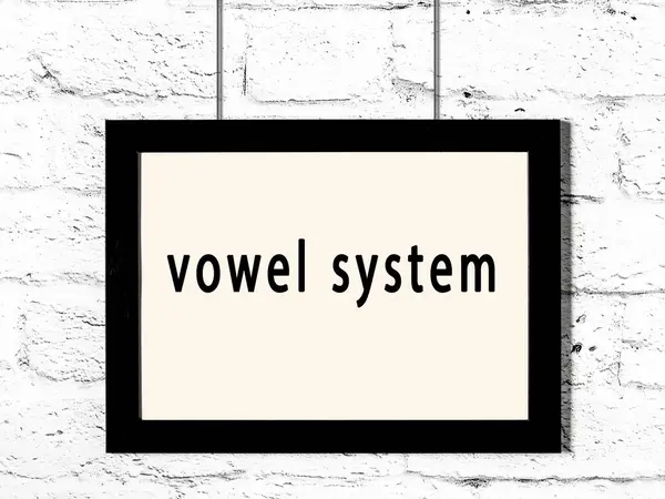 Black Wooden Frame Inscription Vowel System Hanging White Brick Wall — Stock Photo, Image