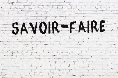 Beyaz tuğlalı duvara siyah boya ile yazılmış yazıtlar..