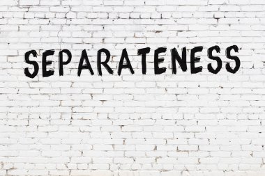 Yazı ayrımcılığı beyaz tuğla duvara siyah boya ile yazılmış..