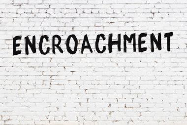 Siyah boyayla yazılmış beyaz tuğlalı bir duvar.