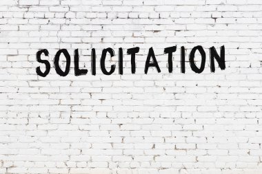 Siyah boyayla yazılmış beyaz tuğlalı bir duvar.