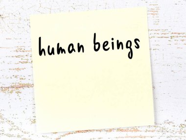 Tahta duvarda el yazısıyla yazılmış sarı yapışkan bir not.