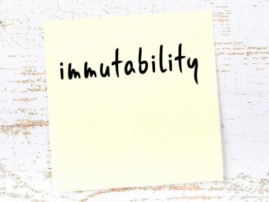 Değişmezlik hakkında hatırlatma kavramı. Tahta duvarda üzerinde yazı olan sarı yapışkan kağıt.