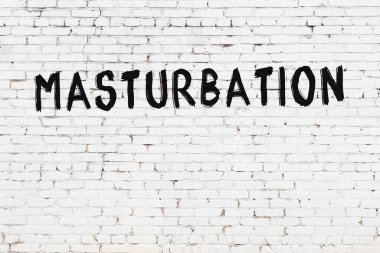 Beyaz tuğla duvara siyah boya ile yazılmış mastürbasyon..