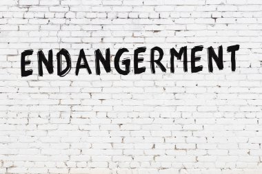 Beyaz tuğla duvarda siyah boyayla yazılan yazıtlar..