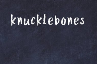 Tebeşir el yazısıyla yazılmış parmak kemikleri siyah masanın üzerinde.