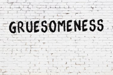 Üzerinde korkunç yazılar olan beyaz tuğla duvar. Siyah boyayla yazılmış.