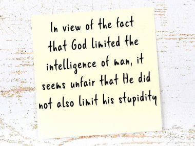 Tahta duvarda asılı sarı yapışkan nota elle yazılmış bilgece bir alıntı.