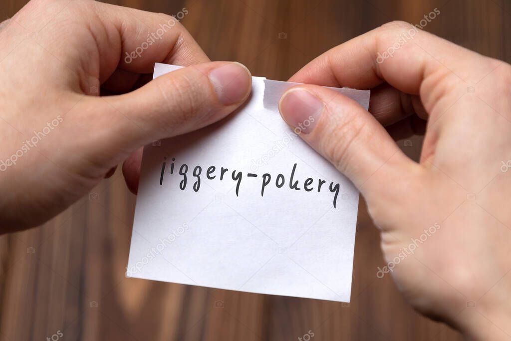 Cancelling jiggery-pokery. Hands tearing of a paper with handwritten inscription.