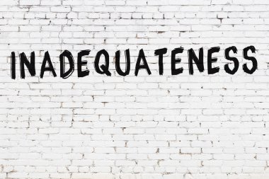 Siyah boyayla yazılan beyaz tuğlalı bir duvar.