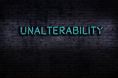 Tuğla duvara karşı değişmezlik yazılı neon levhası. Gece görünümü