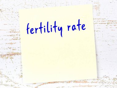 Doğurganlık oranını hatırlatma kavramı. Tahta duvarda üzerinde yazı olan sarı yapışkan kağıt.