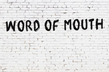 Beyaz tuğladan bir duvar. Ağızdan yazılmış siyah boyayla yazılmış bir kelime.