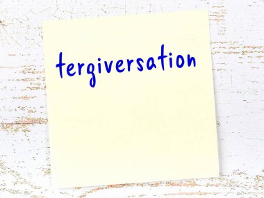 Tahta duvarda el yazısıyla yazılmış sarı yapışkan bir not var.