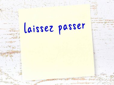 Tahta duvardaki sarı yapışkan notta el yazısıyla yazılmış laissez pasör.