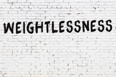 Beyaz tuğla duvara siyah boya ile yazılmış ağırlıksız yazılar..