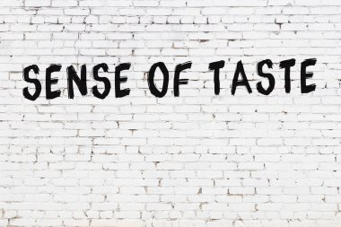 Yazılı beyaz tuğla duvar. Tat alma duyusu siyah boyayla el yazısıyla yazılmış.