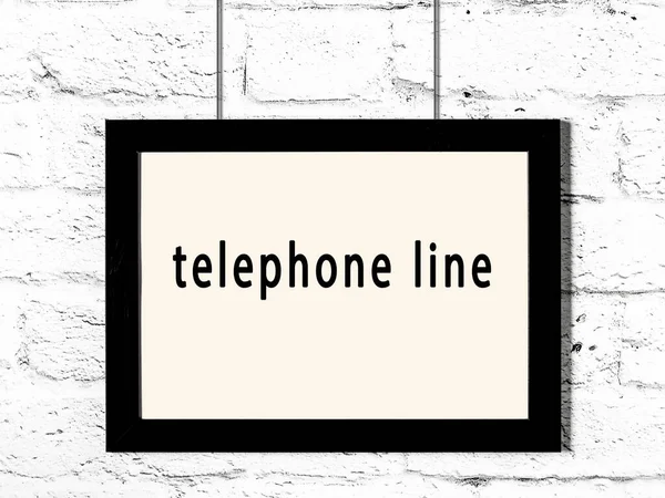 碑文電話線が白いレンガの壁にかかっている黒い木製のフレーム — ストック写真