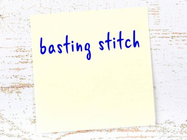 Tahta duvarda sarı yapışkan bir not ve el yazısıyla tutturulmuş dikiş.