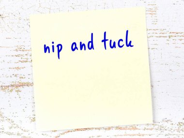 Nip and Tuck 'ı hatırlatma anlayışı. Tahta duvarda üzerinde yazı olan sarı yapışkan kağıt.