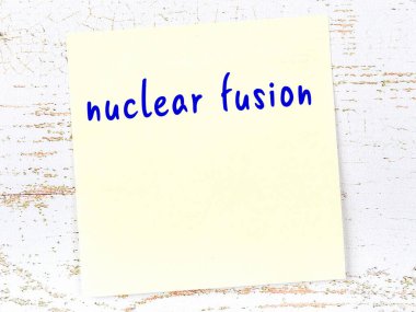 Tahta duvarda el yazısıyla yazılmış nükleer füzyon içeren sarı yapışkan bir not.