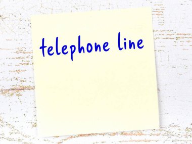 Tahta duvarda el yazısıyla yazılmış telefon hattı olan sarı yapışkan bir not.