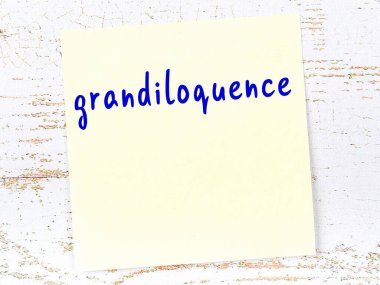 İhtişam hakkında hatırlatma kavramı. Tahta duvarda üzerinde yazı olan sarı yapışkan kağıt.